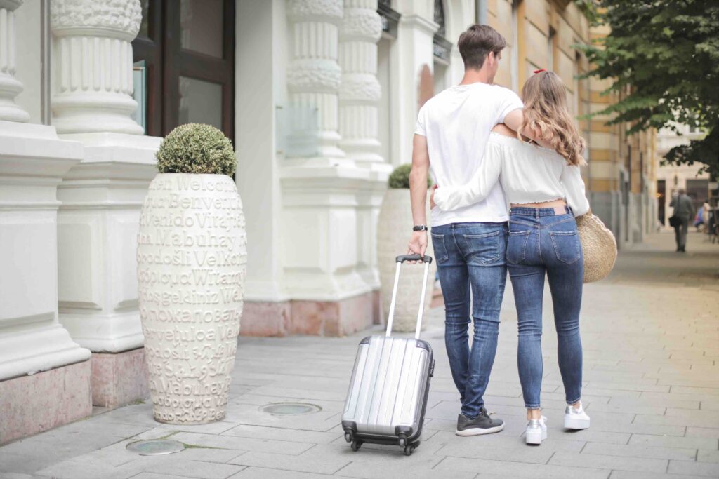 Couple with suitcase walking along city street